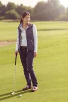 Female golfer standing on green photo