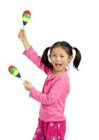 Happy young girl dressed in pink playing maracas photo