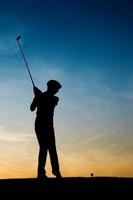Senior female golf player at sunset
