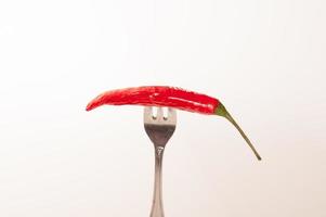 pimiento rojo picante pinchado en el tenedor de acero aislado foto