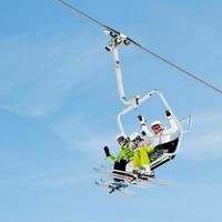 Three skiers riding a ski lift and waving to the camera