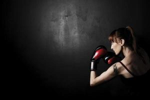 Boxer mujer con guantes rojos sobre fondo negro foto