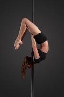 woman exercise pole dance on gray background photo