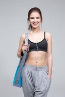 Happy fit woman standing with yoga mat photo