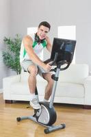 Smiling handsome man training on exercise bike using laptop photo