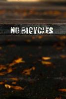 No Bicycles Painted Sign on Old Rusty Metal Fence photo