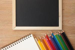 color pencils with notebook and blackboard photo