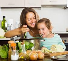 feliz madre con hija cocinando juntos foto