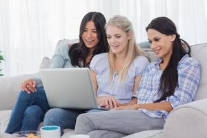 Smiling friends looking at laptop together photo