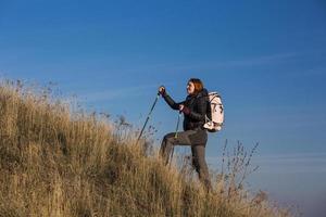 mochilero femenino asciende colina empinada foto
