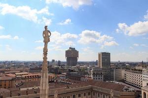 Cathedral statue and view of Milan cityscape with Torre Valesca