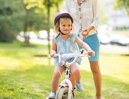 mother and baby girl riding bicycle outdoors