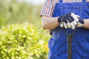Midsection of gardener holding spade in plant nursery photo