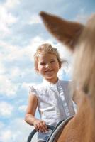 Young girl riding a pony on a sunny day photo