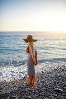 mujer en vestido despojado con un sombrero en la playa