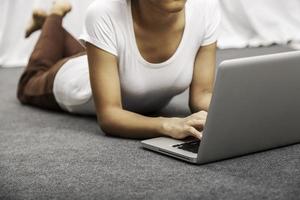 young woman laying while using laptop photo