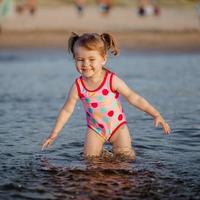 Adorable baby girl playing with a water in the sea photo