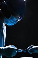 Cirujanos pasando equipo quirúrgico en el quirófano, oscuro, primer plano foto