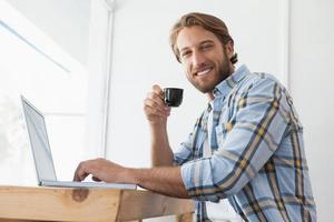 Hombre casual usando laptop bebiendo café exprés foto