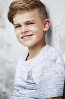 Portrait of young boy leaning against wall photo