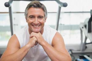 Fit man smiling at camera in fitness studio photo