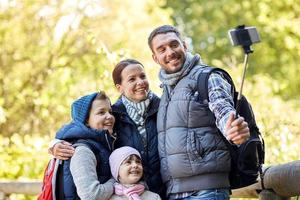 happy family with smartphone selfie stick in woods photo