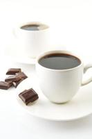 Cups of coffee with chocolate and saucers on white photo