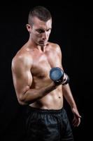 Handsome shirtless athlete working out with dumbbell photo
