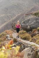 aptitud. mujer joven corriendo en una carretera de montaña foto