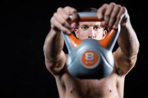 Confident shirtless athlete showing kettlebell photo