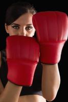 Vista frontal de la joven deportiva posando con guantes de boxeo