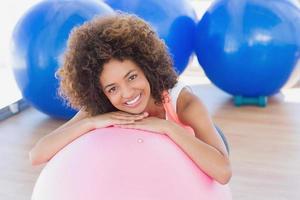 mujer joven sonriente con pelota de fitness en el gimnasio