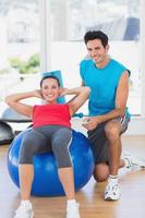 Entrenador masculino ayudando a la mujer con sus ejercicios en el gimnasio foto