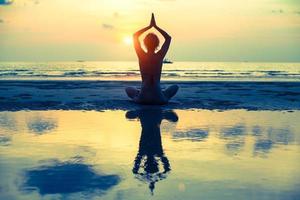 Yoga mujer sentada en postura de loto en la playa foto