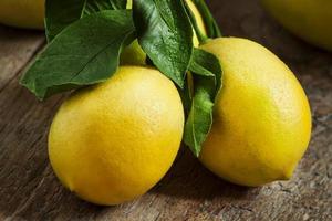 limones frescos y jugosos con hojas en la vieja mesa de madera