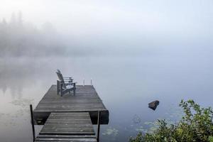 Chairs on a Dock Overlooking a Misty Lake photo