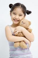 niña bonita jugando con muñeca oso foto