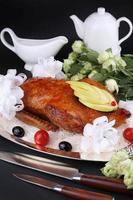 Roasted duck stuffed with apple, garnished cherry tomatoes and olives photo