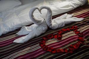 Bed with heart and swans made of towels photo