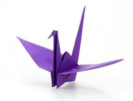 Traditional Japanese origami crane made of purple paper over whi