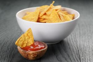 chips de tortilla en un tazón blanco con salsa de tomate en la mesa