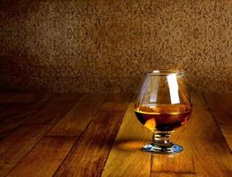 One glass of brandy on antique wooden counter top