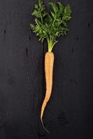 Carrot with green leaves over wooden background. Vegetable. Food photo