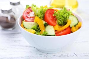 Fresh vegetable salad on white wooden background photo