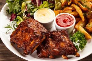 Grilled ribs, chips and vegetables photo