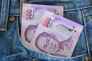 500 billetes tailandeses en el bolsillo de los vaqueros azules foto