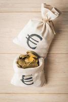 bolsas de dinero y monedas de euro sobre fondo de madera foto