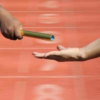 Relay-athletes hands sending action on blur race track  startin photo