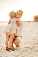 mother and baby girl hugging on beach at the evening