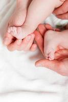 Closeup of baby feet with hands from parents. Studio shot.